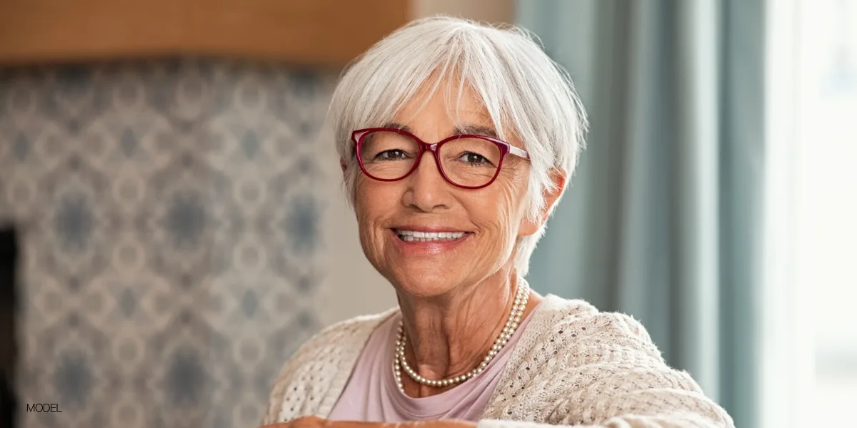Lady with white hair and glasses smiling